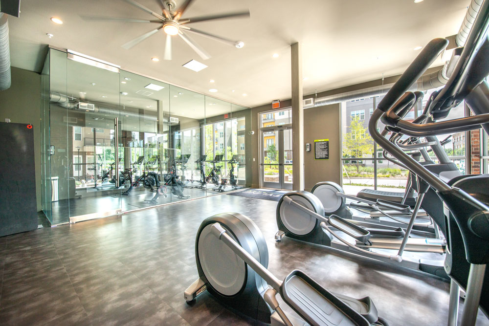 Fitness center with cardio elliptical machines, large mirrored wall and large ceiling fan