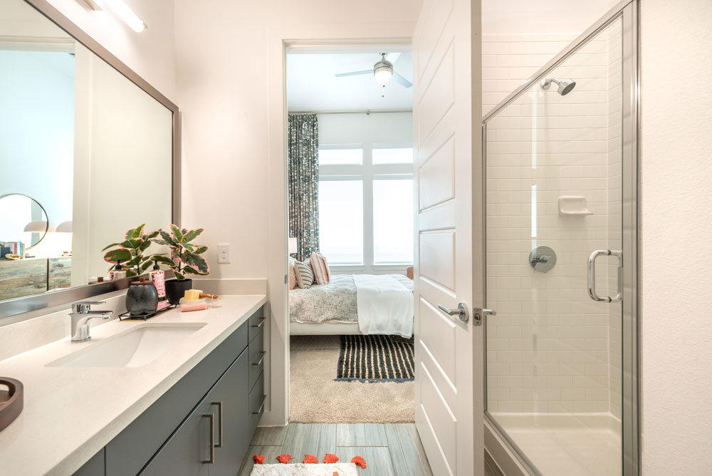 Bathroom with quartz countertops, walk-in shower, single sink vanity and framed mirror