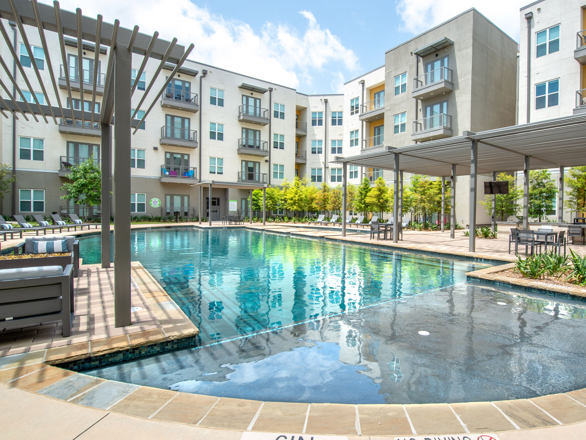 Resort style pool with tanning ledge, covered plush seating, lounge chairs and professional landscaping