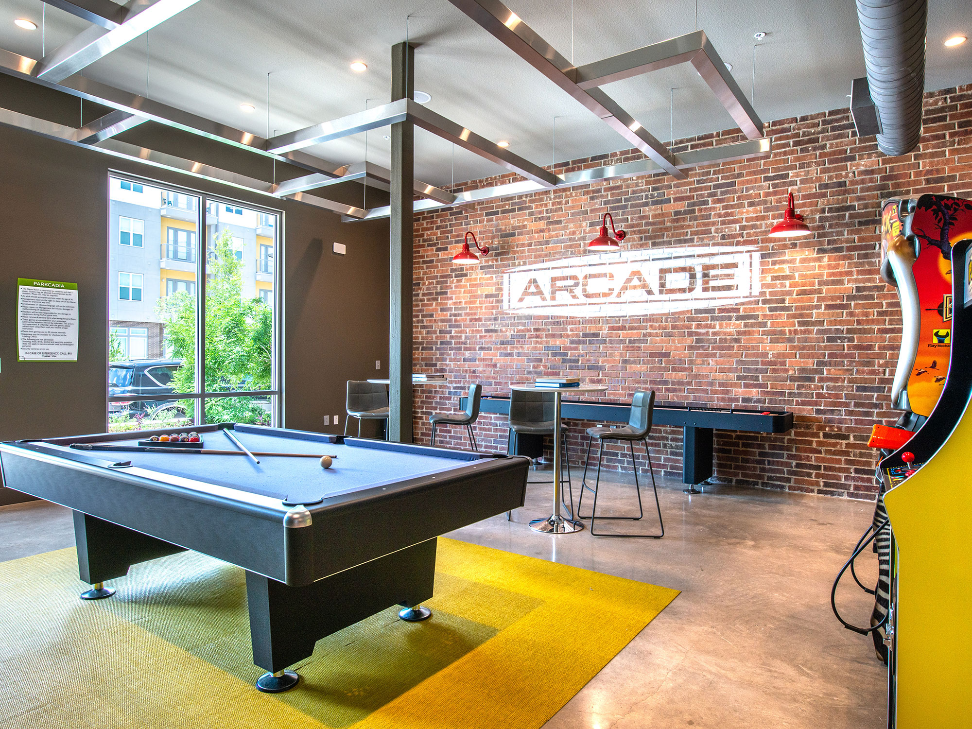 Clubhouse interior with shuffleboard, arcade games pool table and high bar seating